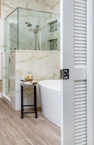 Master bathroom remodel with sophisticated style: marble style tile, glass shower, free standing tub