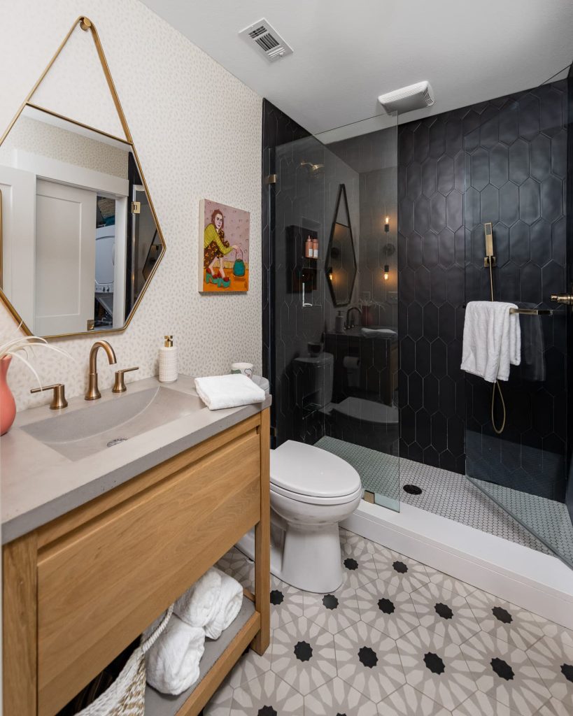 Unique tile floor, black shower, Brass Mirorr, Vanity