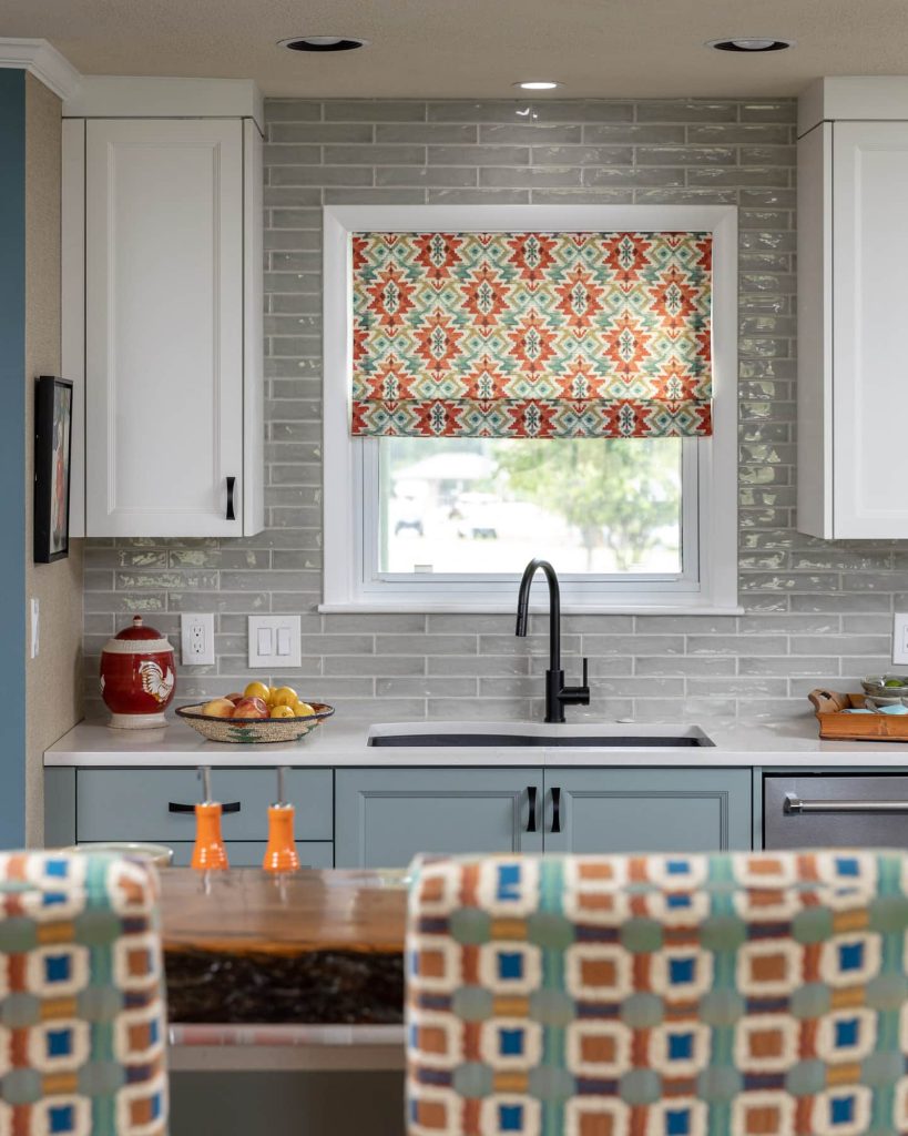 blue cabinets, grey backsplash, wood bar top, white cabinets, black cabinet hardware, barstool, window treatment